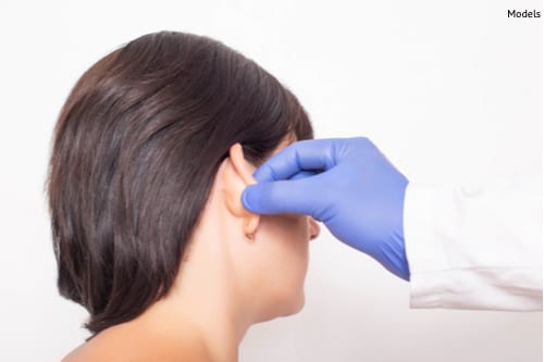 A plastic surgeon examines a patient's ear before surgery.