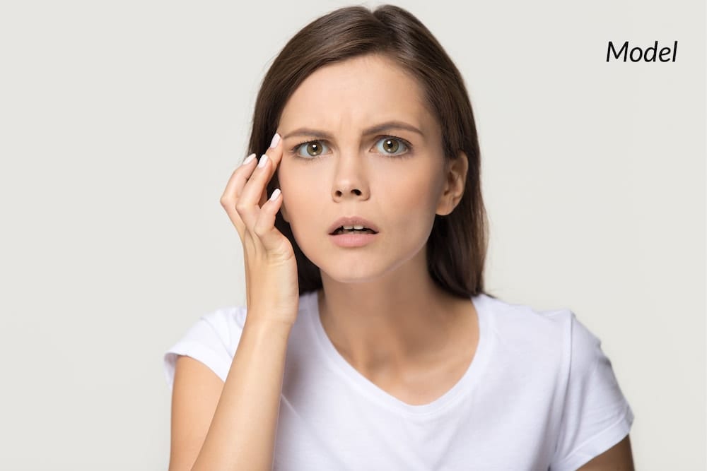 Young woman checking her forehead for wrinkles.