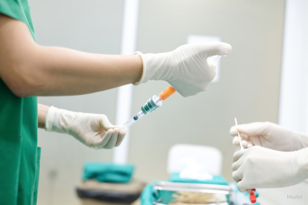 Surgeon holding syringes of purified fat for fat transfer.