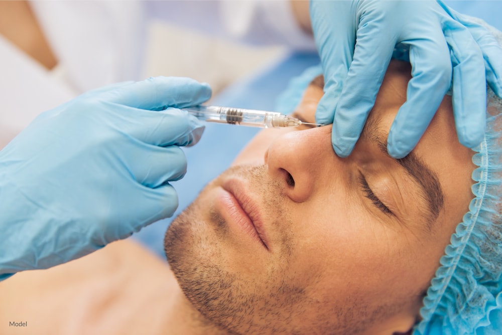 Man undergoing a BOTOX® Cosmetic injection between the eyebrows with his plastic surgeon.