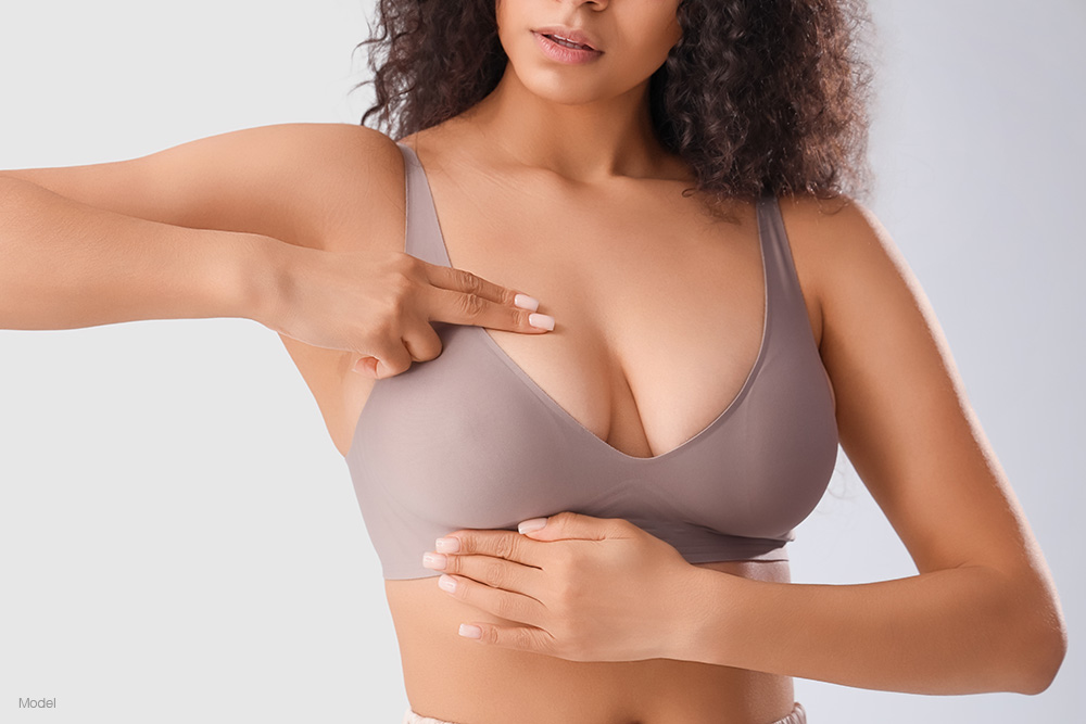 Woman in a tan bra holding her breasts